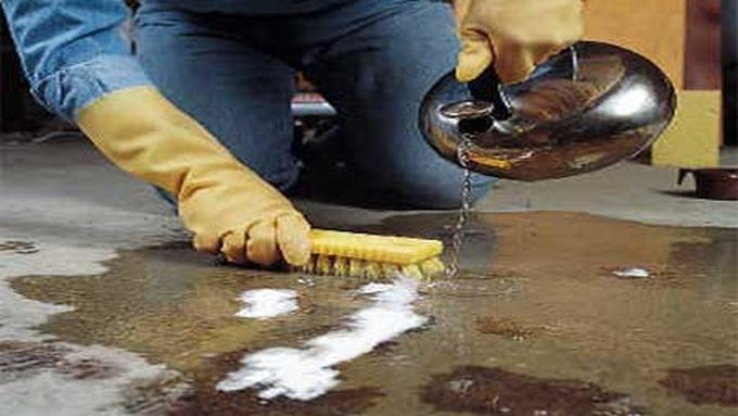 A man pouring a cleaning fluid and scrubbing a grease stain