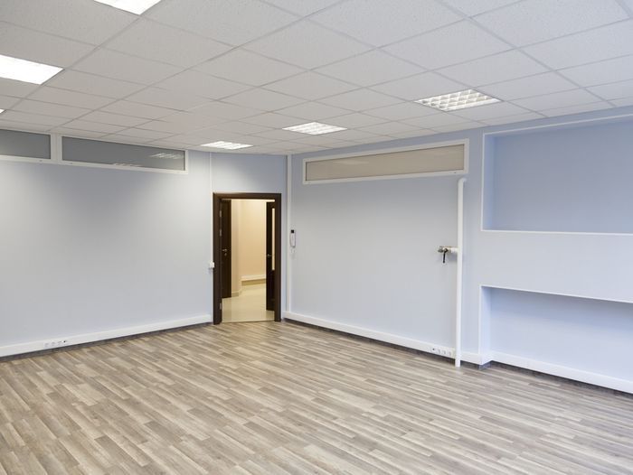 An empty room with an open door in the corner and a drop ceiling.