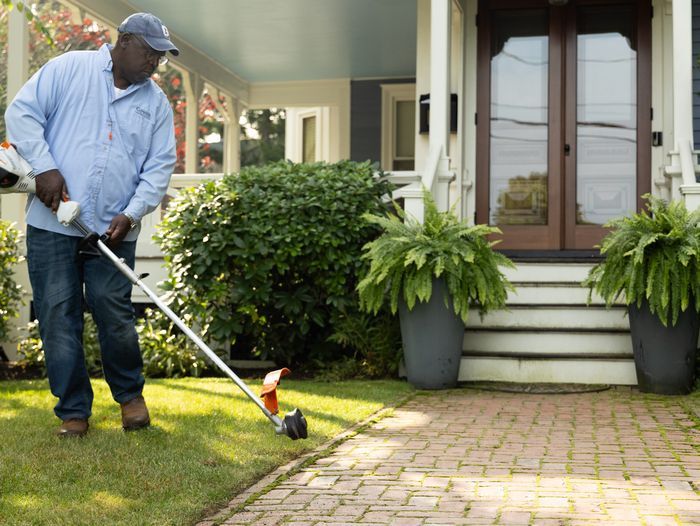 Lee Gilliam using a string trimmer to clean up a walkway