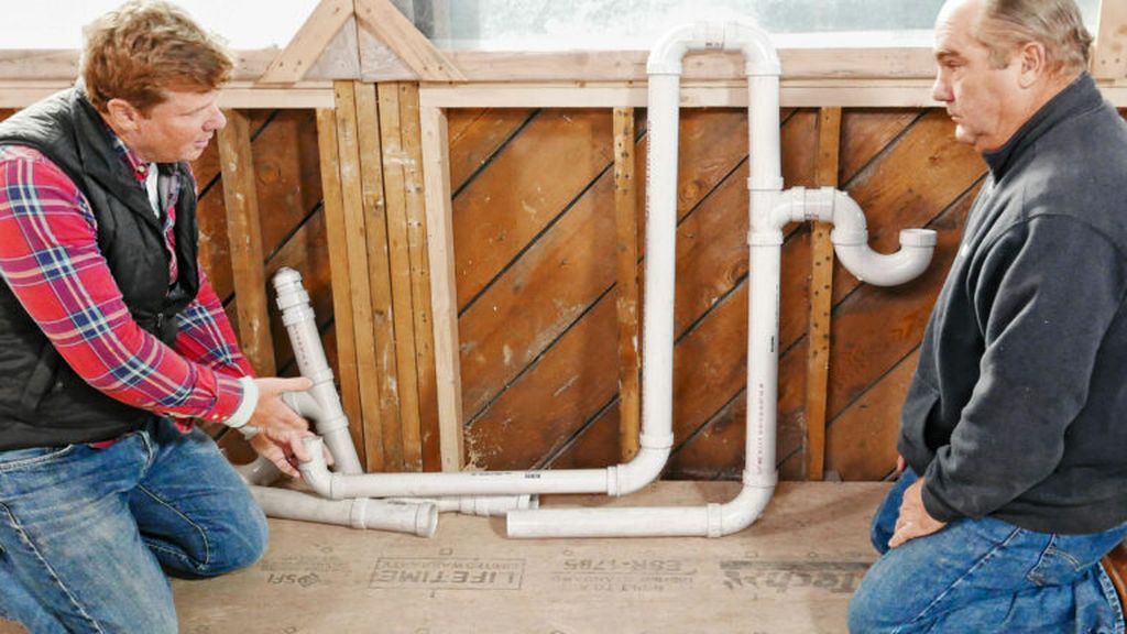 Kevin O'Connor and Richard Trethewey look at PVC pipes that are part of a plumbing project.