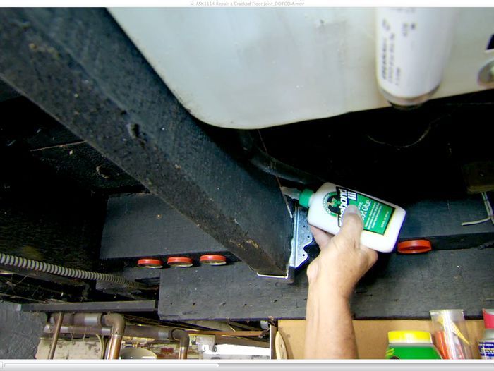 A man applying glue to a cracked joist.